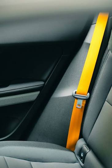 A bright amber seatbelt webbing strap running down the rear cabin of a vehicle beside the seat.