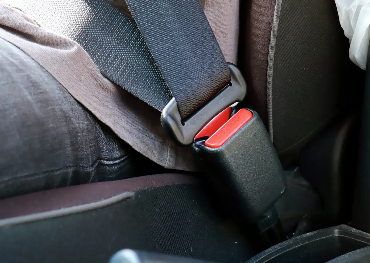 A fastened seatbelt showing the webbing, tongue plate and receiver in place across a vehicle seat.